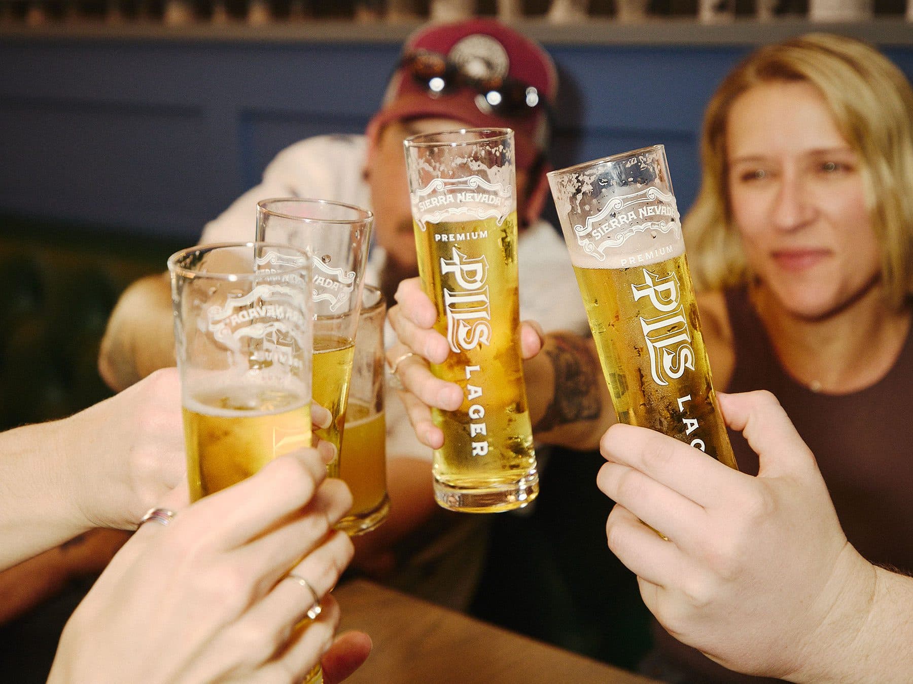 A group of friends raising glasses of Sierra Nevada PILS in a cheers
