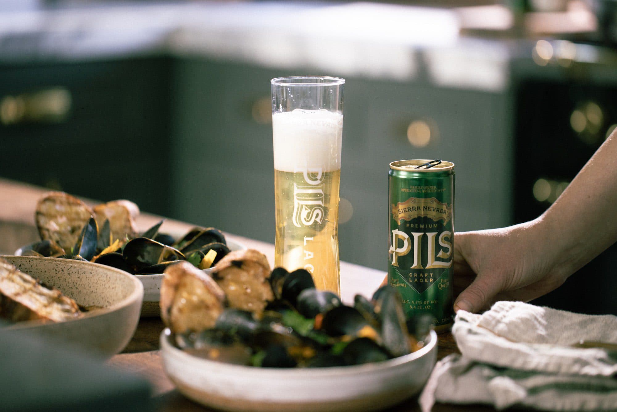 PILS in can and glass next to bowl of steamed mussels.